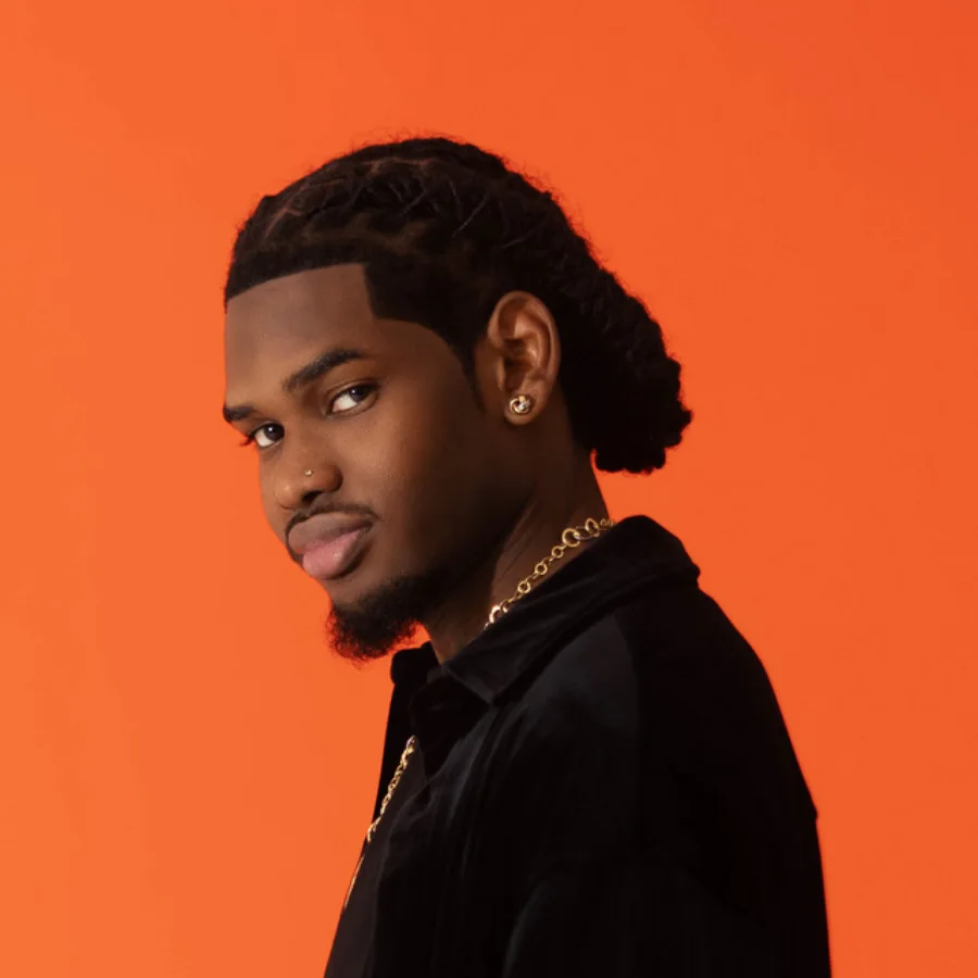Portrait de 1T1, artiste et producteur guadeloupéen, fondateur du label KMR Héritage, sur fond orange